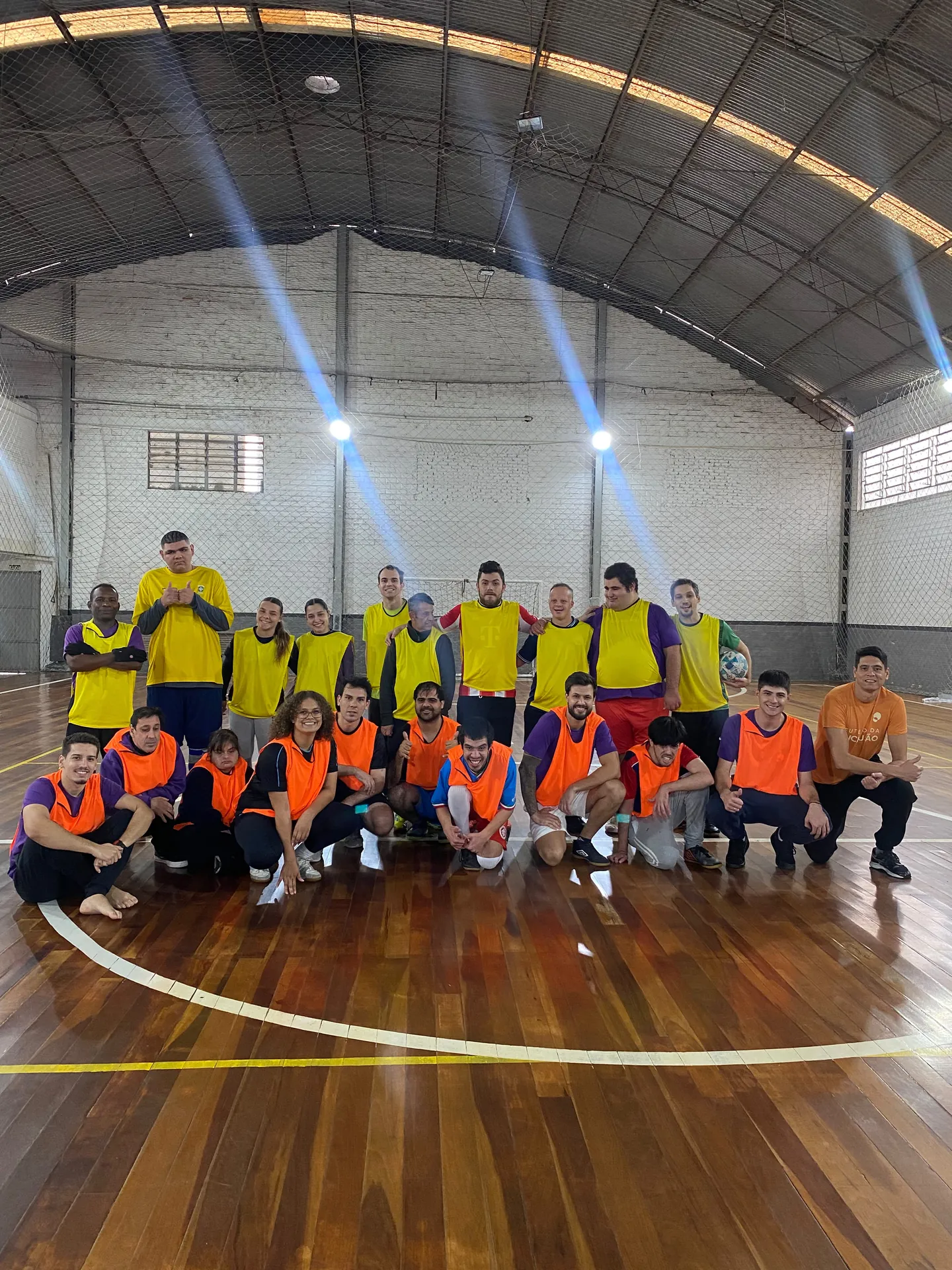 Time de futsal do Pertence posa na quadra, com coletes coloridos.