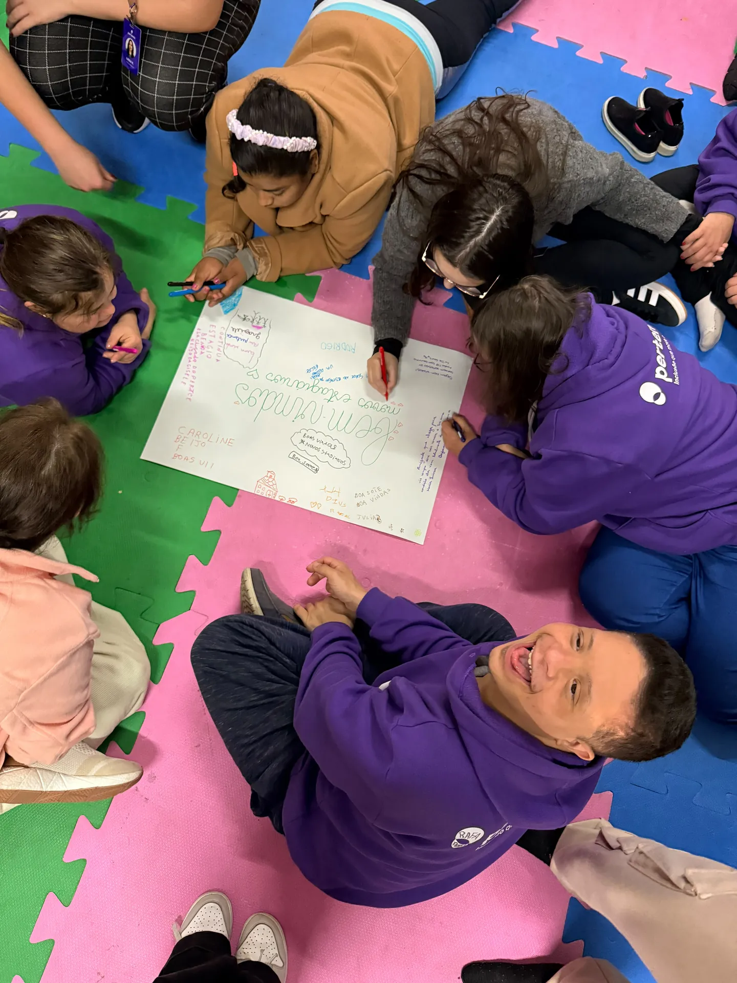 Grupo deitado em roda no tatame preenche um painel de papel sobre emoções.