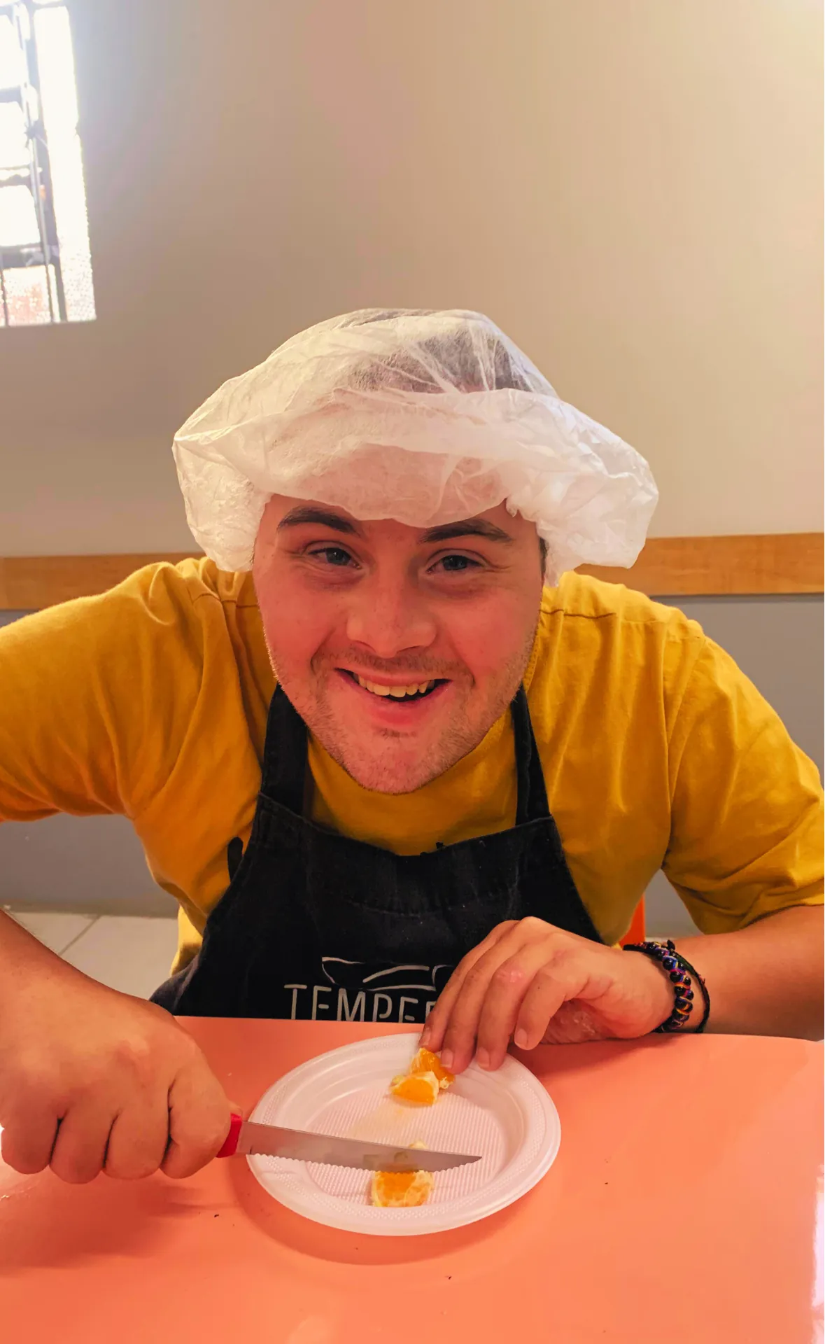 Participante de touca e avental prepara um prato na oficina de culinária.