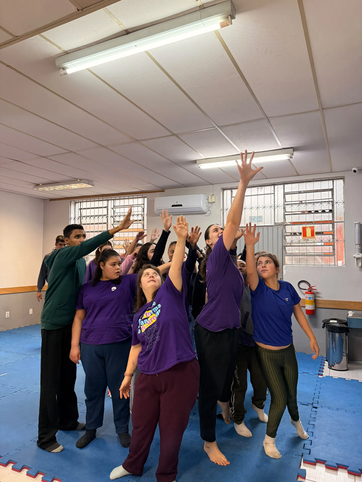 Turma da oficina de dança com os braços erguidos no salão.