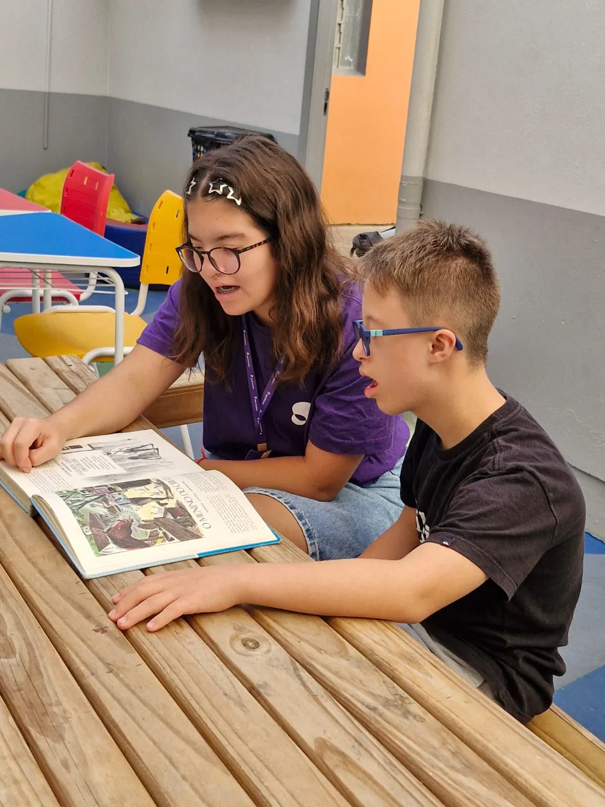Educadora e participante leem juntos um material na oficina de idiomas.