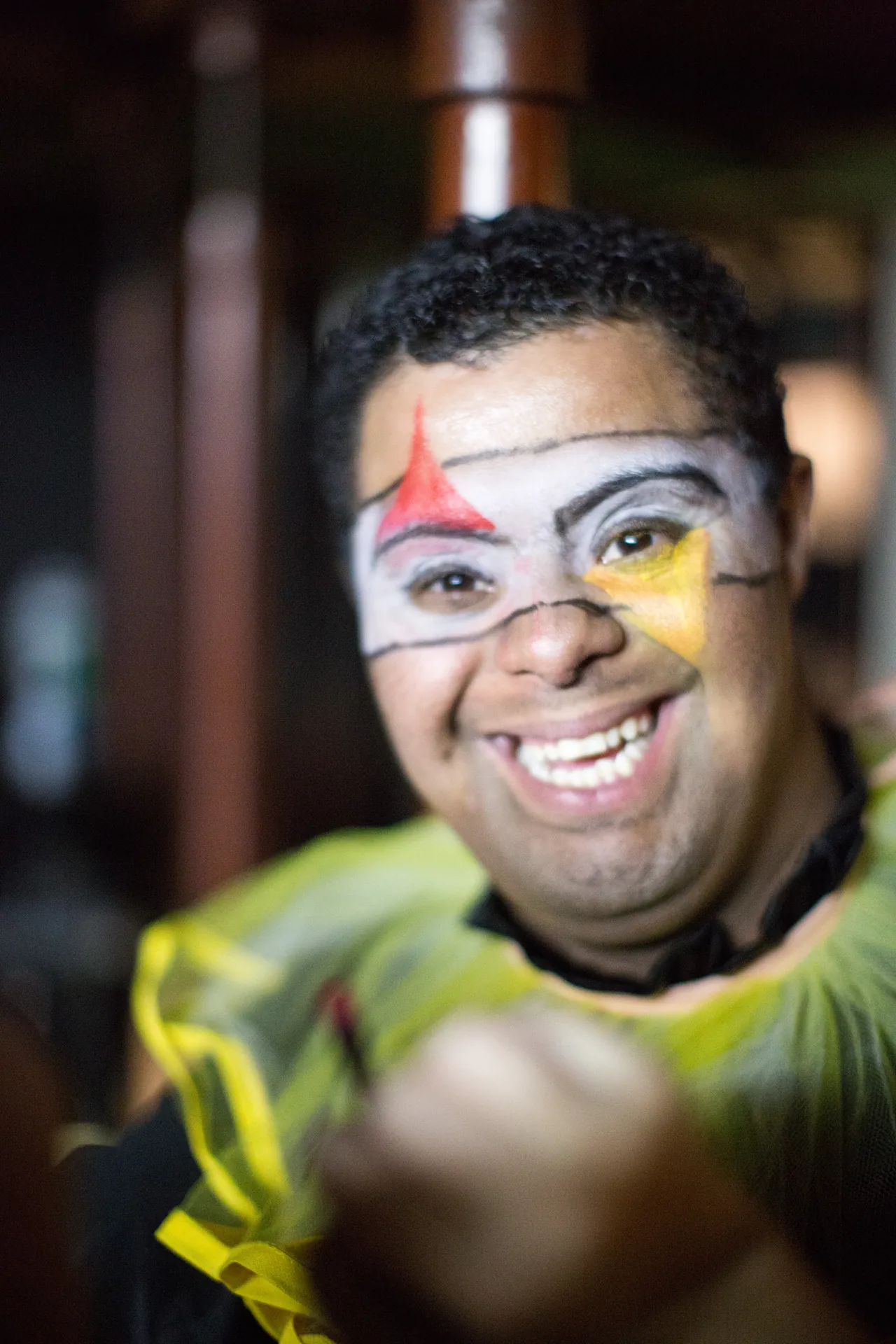 Participante da oficina de teatro com o rosto pintado, sorrindo.