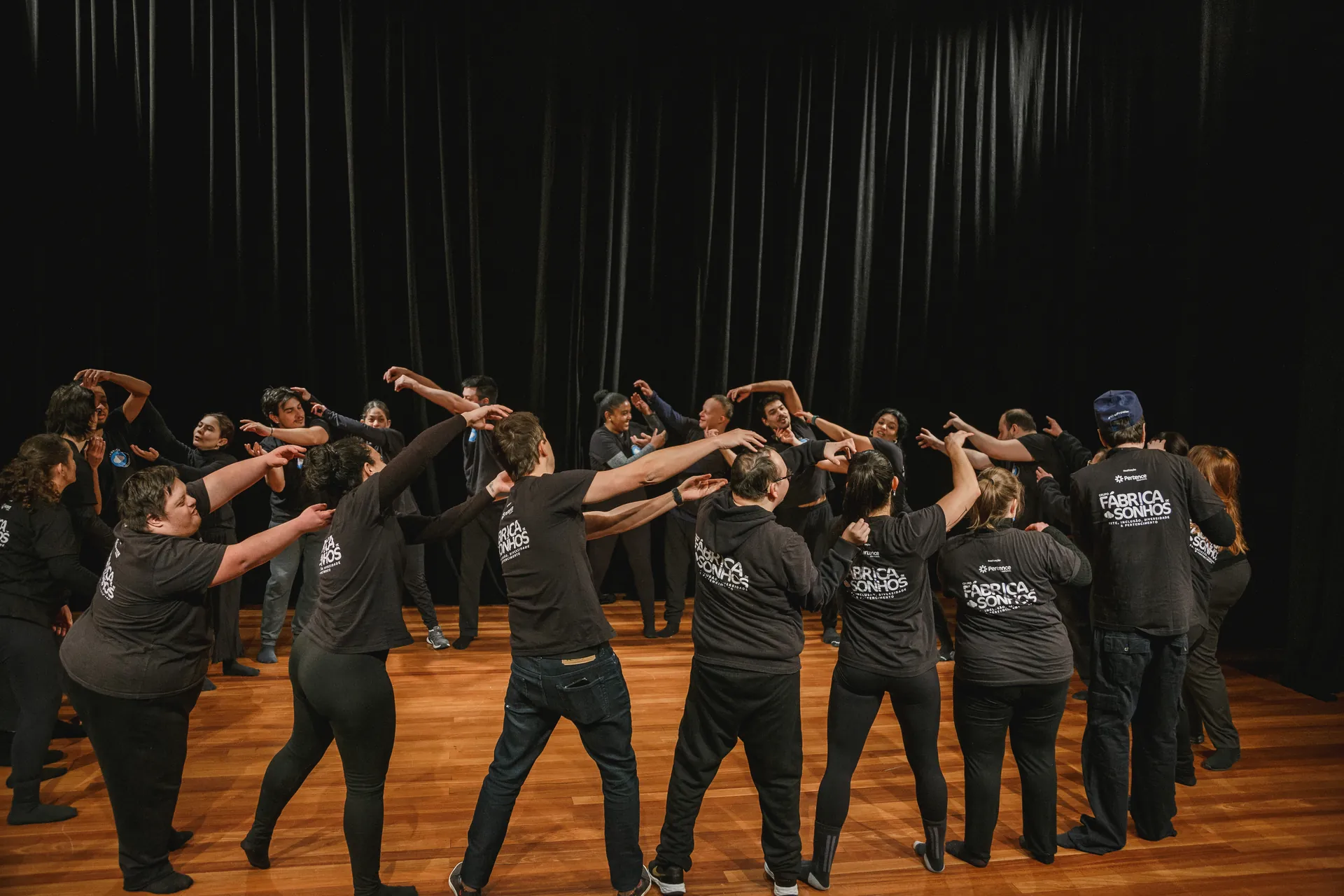 Elenco em movimento coreografado no palco.