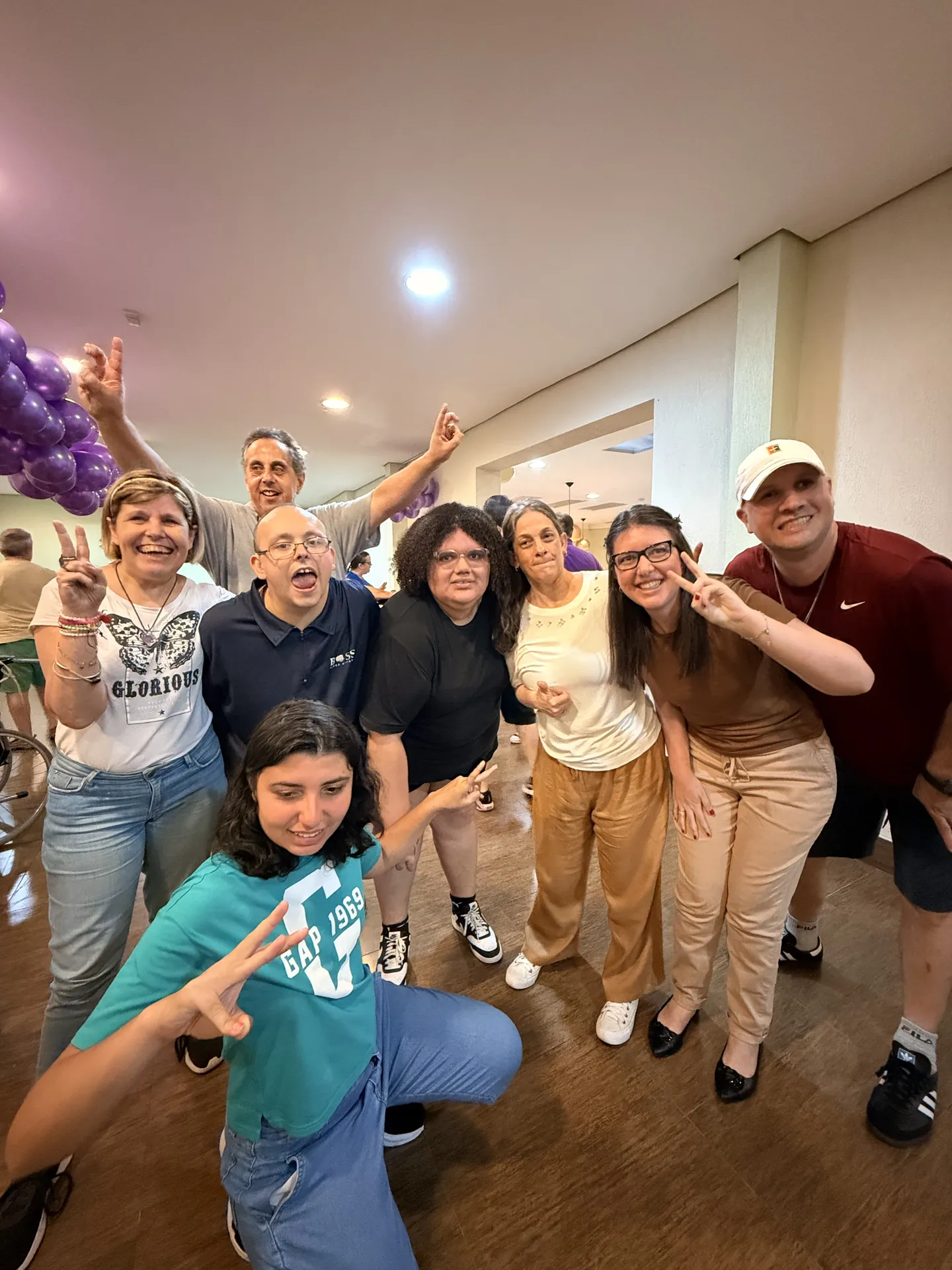 Grupo do Pertence posa sorrindo numa festa decorada com balões.