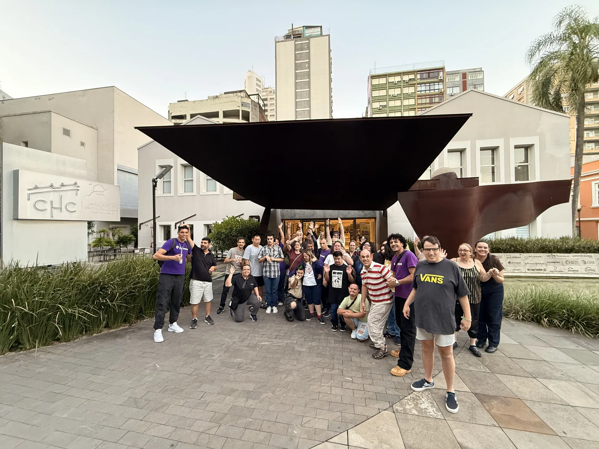 Grupo posa em frente à escultura na entrada de um centro cultural.