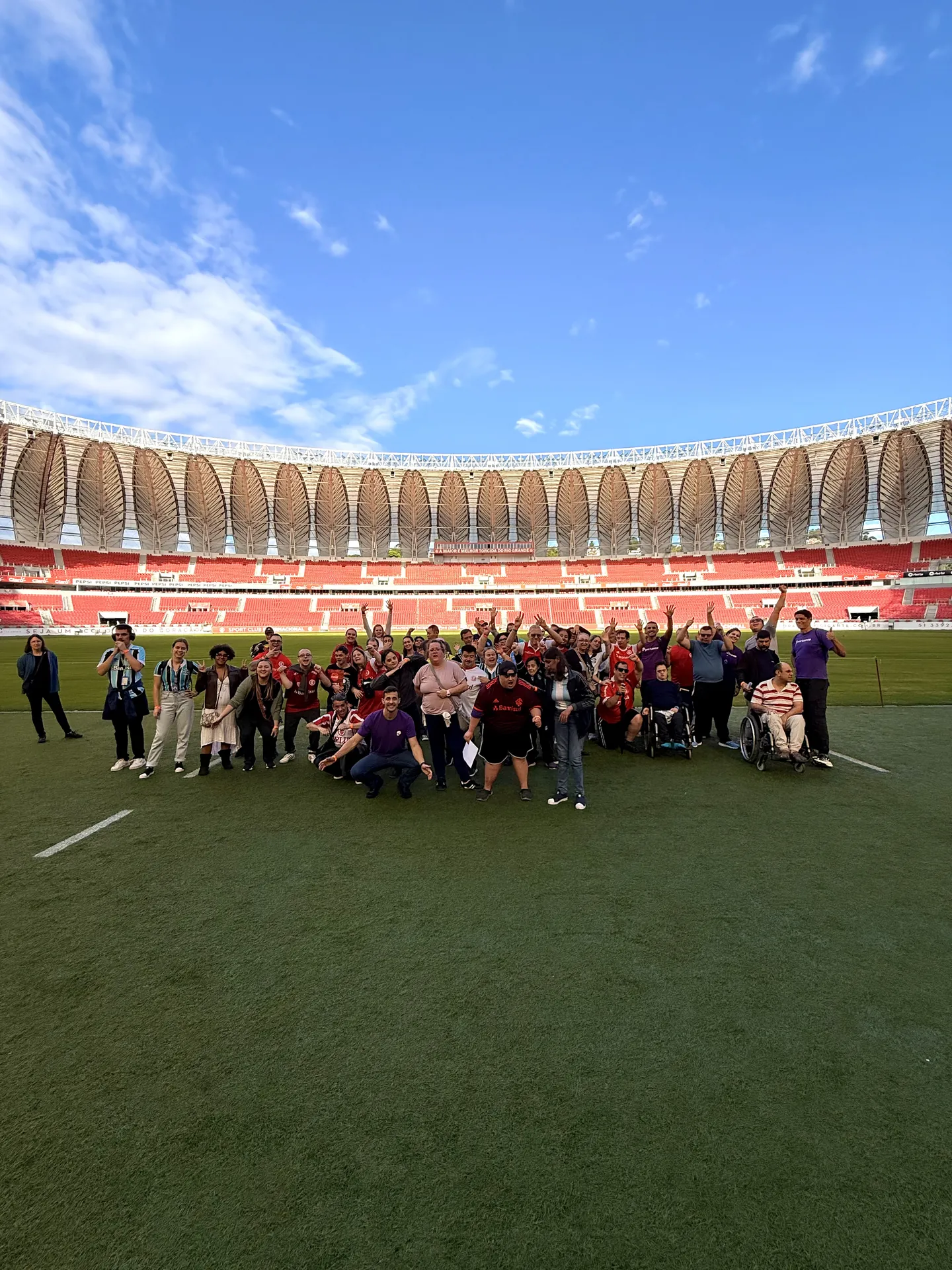 Grupo grande do Pertence reunido no gramado de um estádio de futebol.