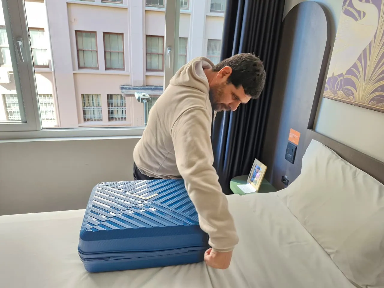 Participante arruma a própria mala sobre a cama do quarto.