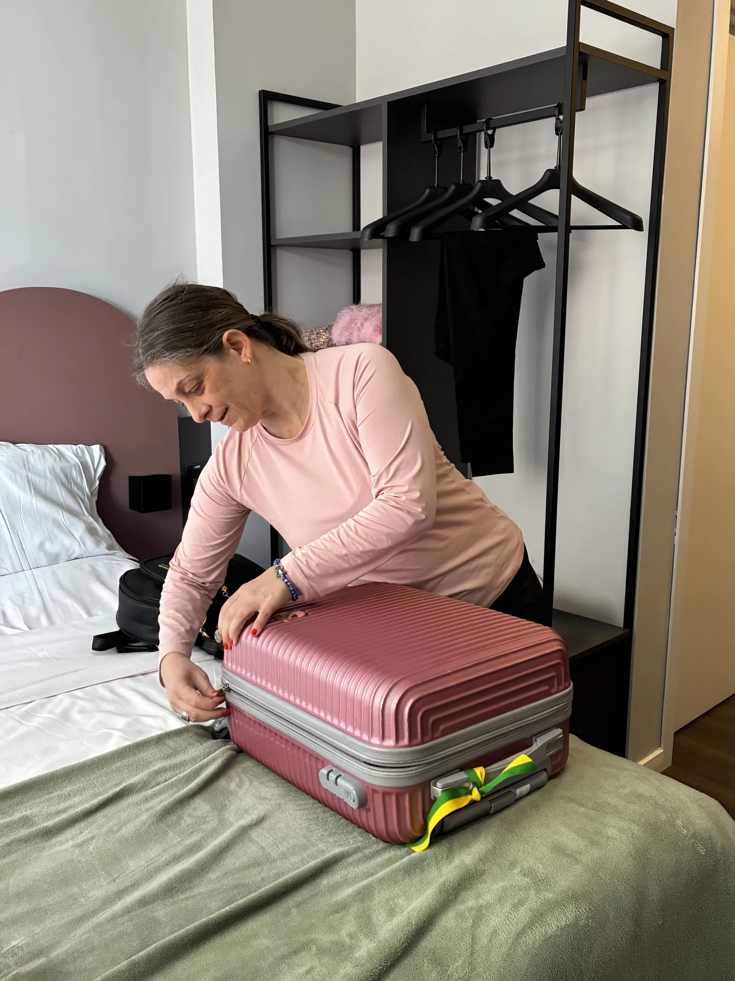 Participante organiza a mala aberta sobre a cama do quarto.