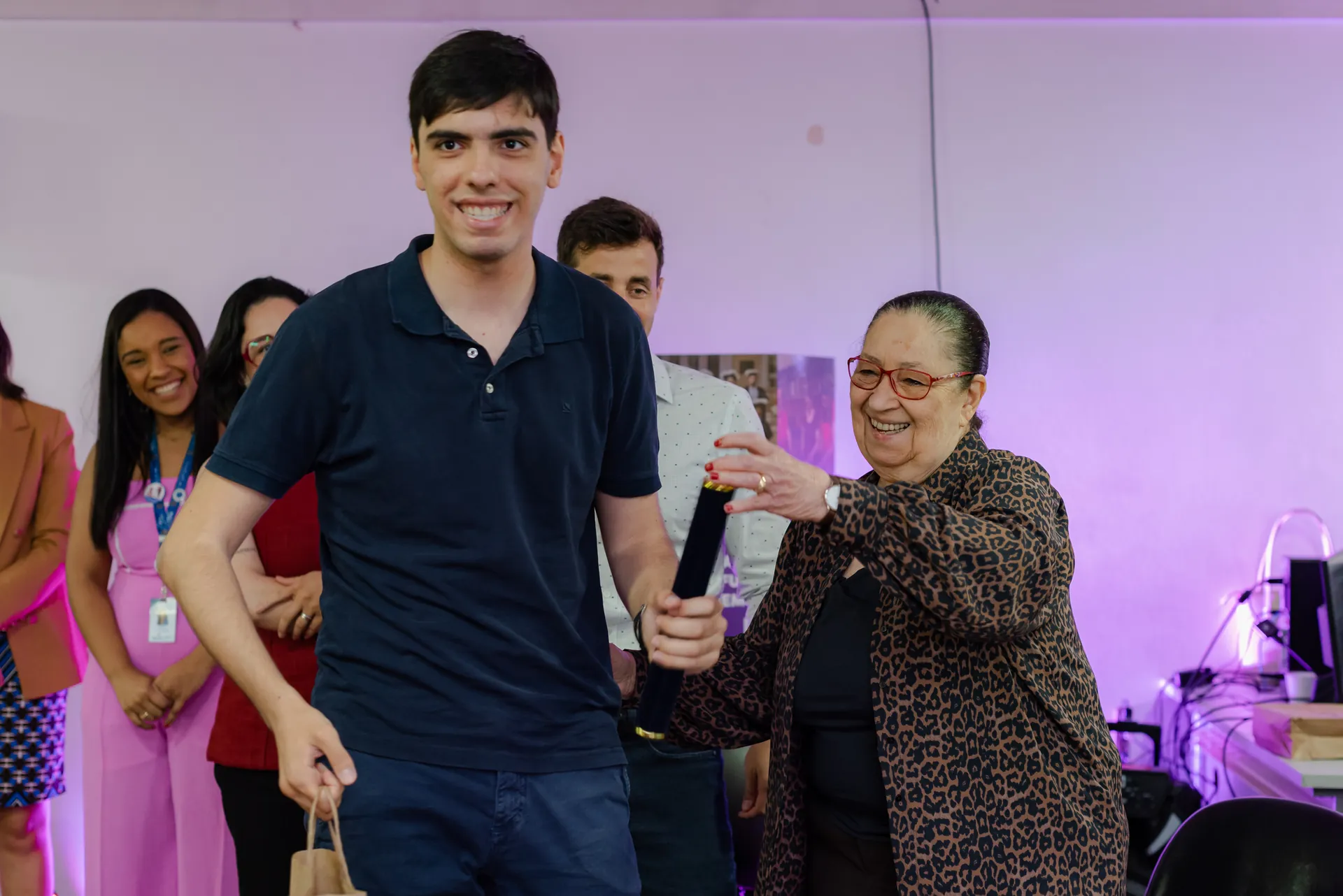 Participante recebe o certificado das mãos de uma educadora.