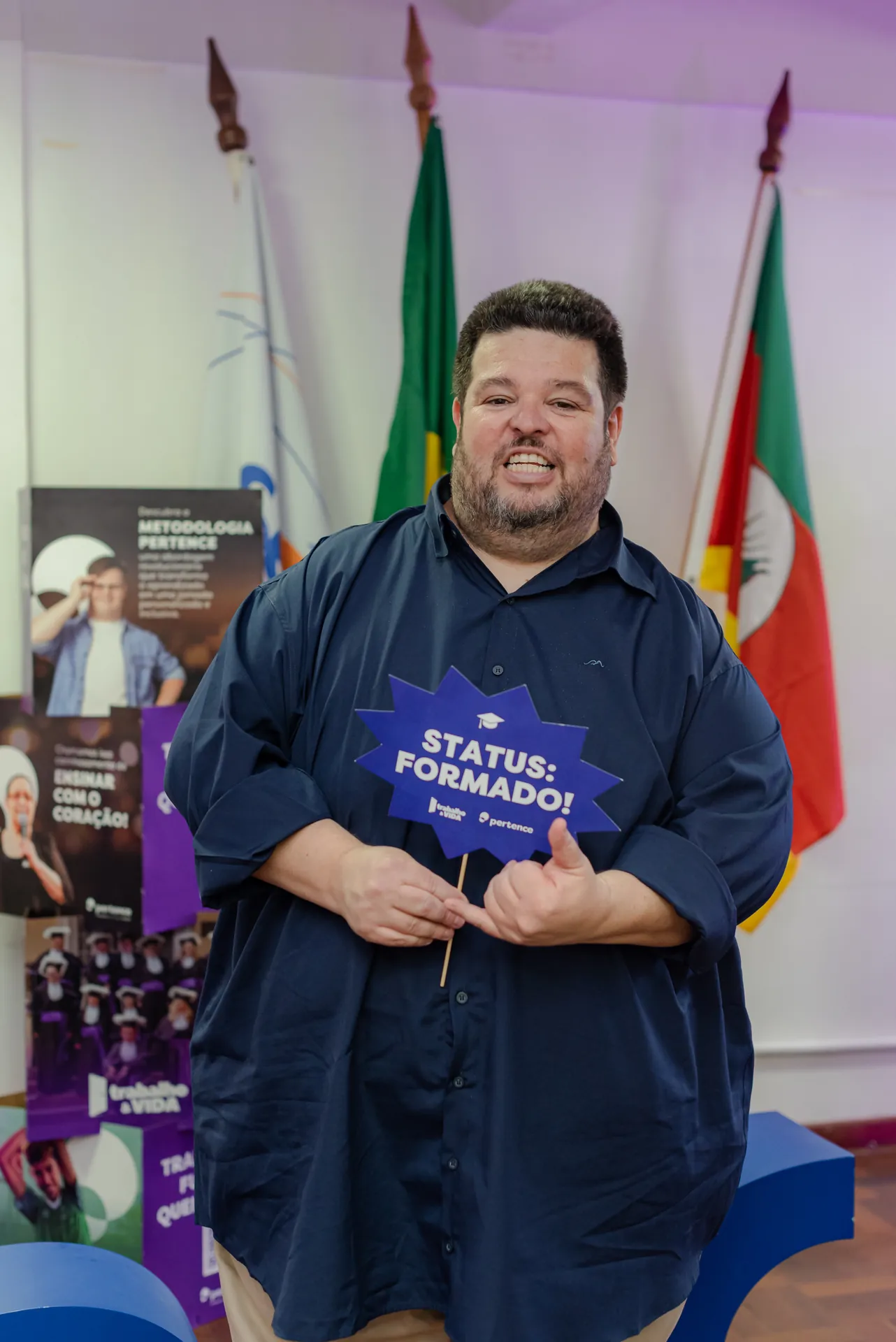 Participante segura uma placa escrita “Status: formado”.