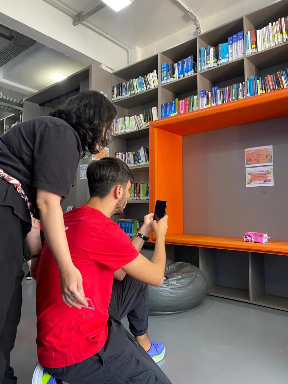 Participante fotografa um colega na biblioteca.