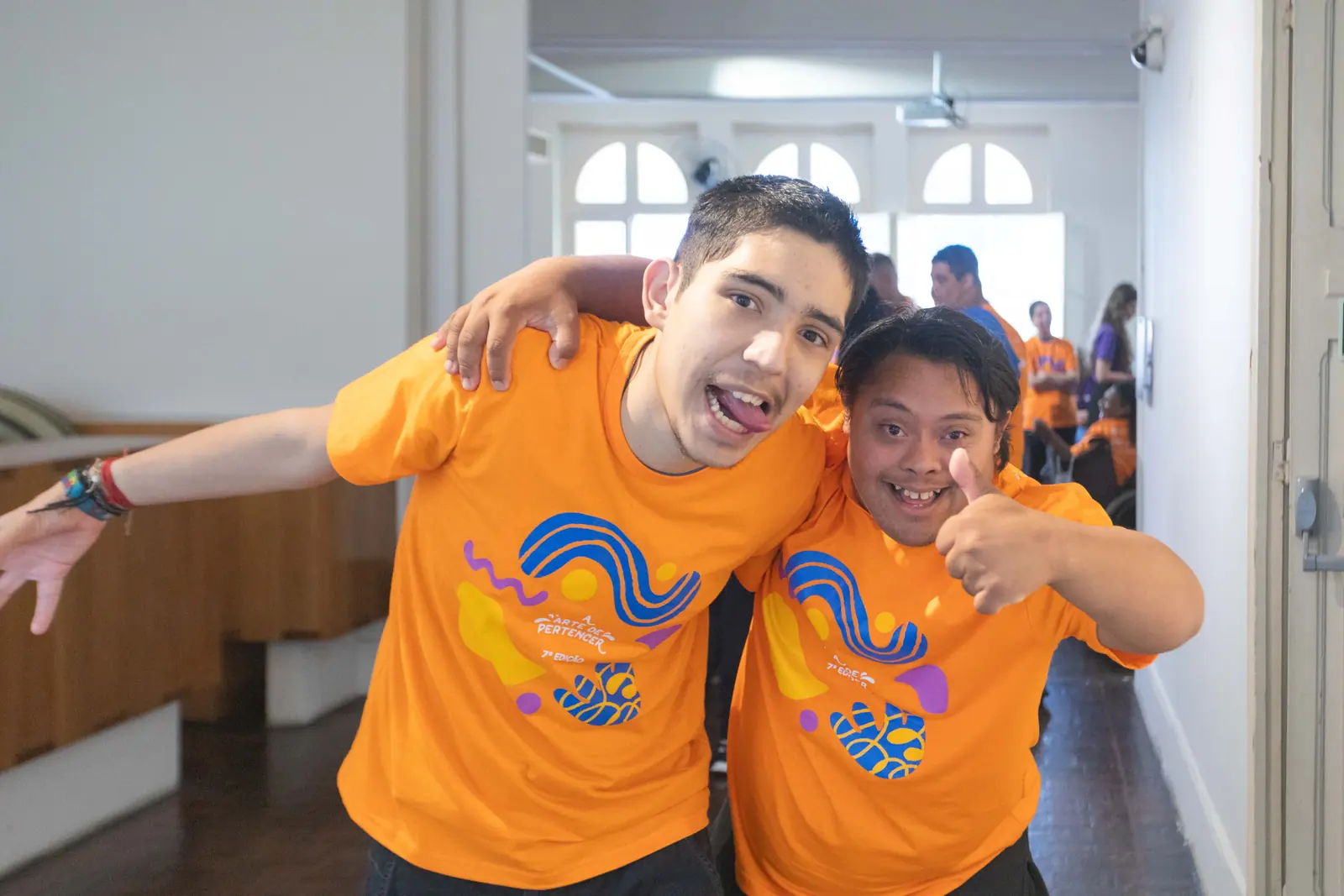 Dupla de participantes abraçada nos bastidores, sorrindo para a câmera.