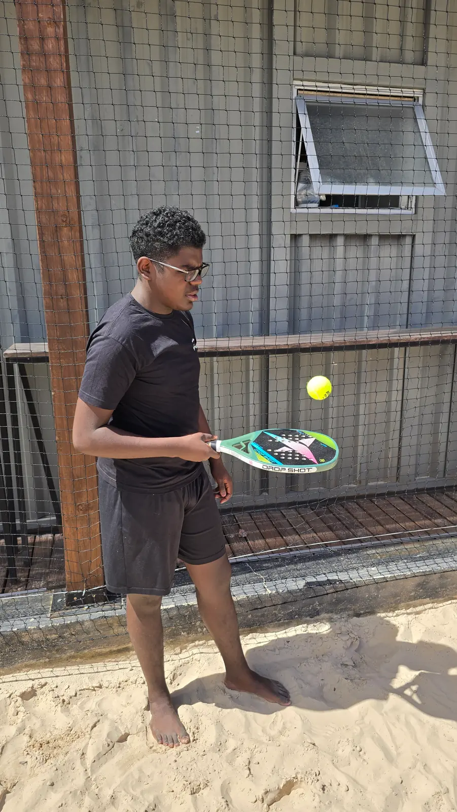 Aluno de raquete em punho, pronto para rebater a bola.