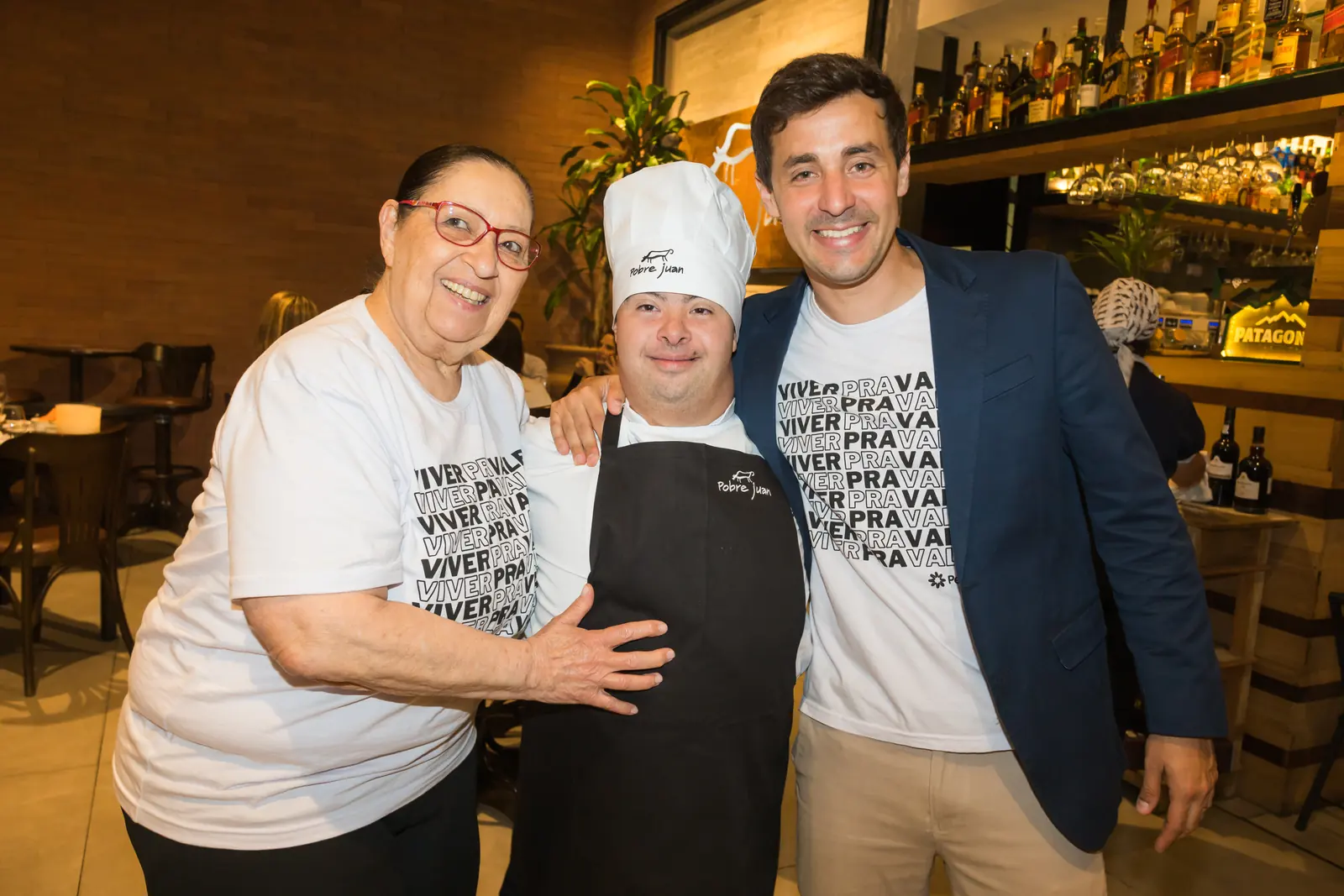 Participante entre dois convidados do jantar, todos sorrindo.