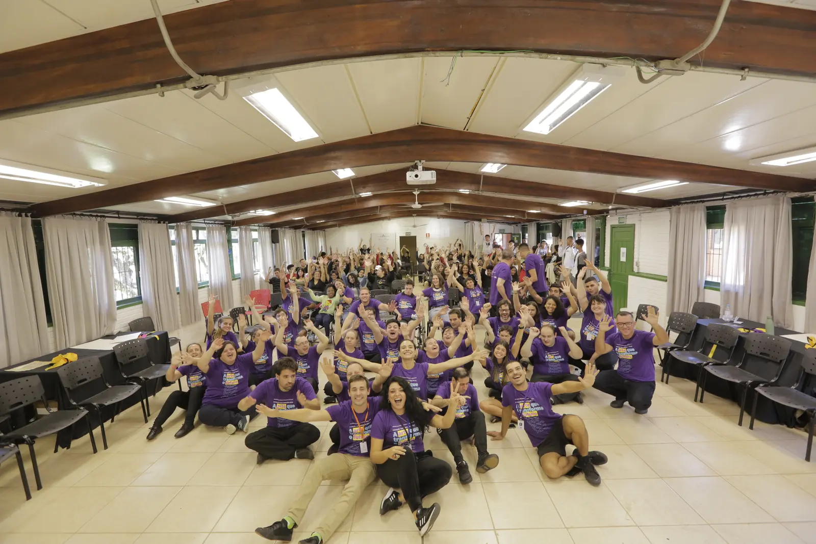Turma inteira reunida no salão, sentada no chão para a foto de grupo.