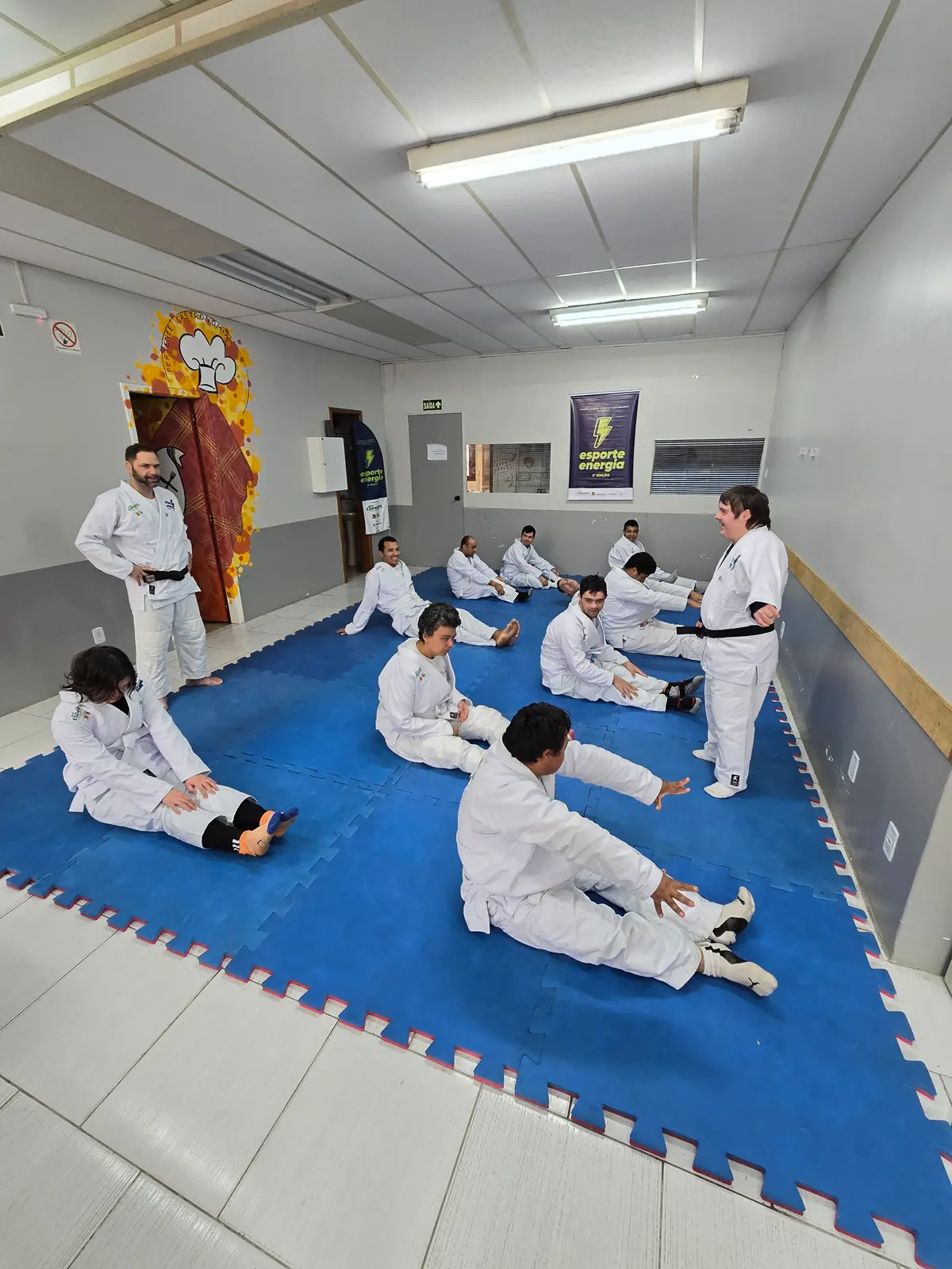 Turma sentada no tatame durante o alongamento.