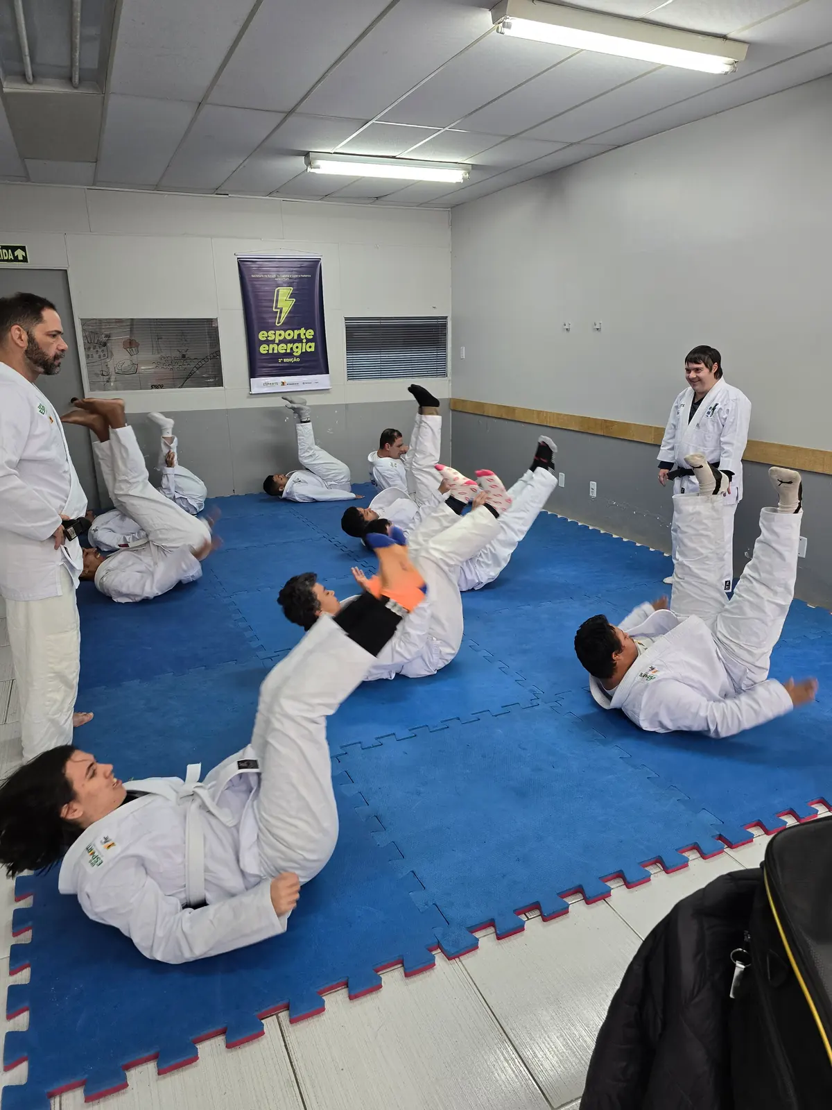 Alunos de quimono treinando movimentos de jiu-jitsu no tatame.