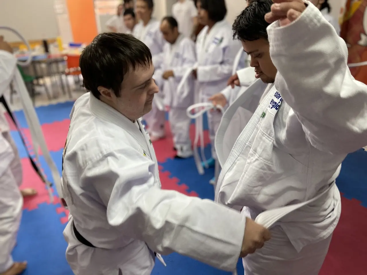 Dupla treina uma pegada de judô durante a aula.