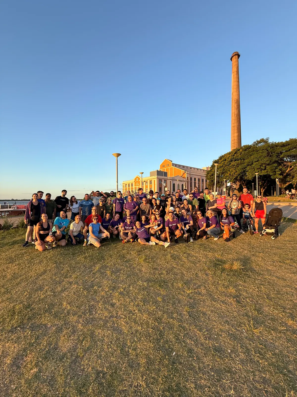 Grupo reunido para a foto na orla, com o pôr do sol ao fundo.