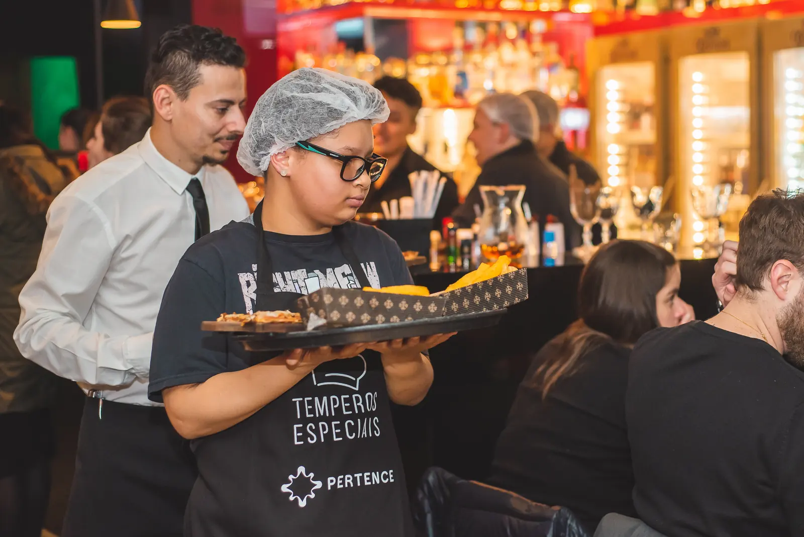 Participante circula pelo salão servindo uma bandeja de canapés.