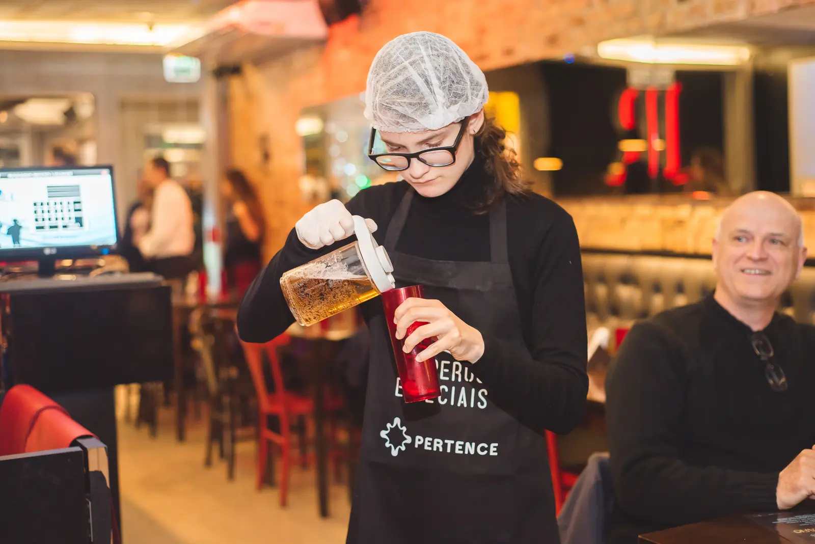 Participante serve chope em uma taça no evento.